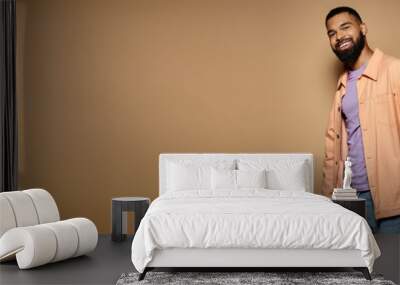 Handsome African American man in fashionable attire posing in front of a vibrant brown wall. Wall mural