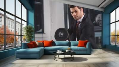 handsome businessman in suit training with dumbbell in sports center Wall mural