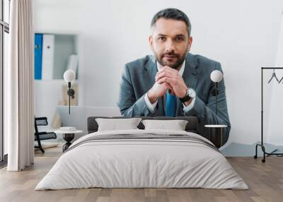 handsome businessman sitting at table with laptop and looking at camera in office Wall mural