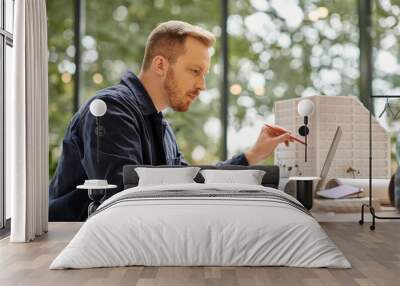 handsome concentrated man in casual attire working on his startup with his laptop in office Wall mural