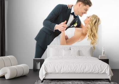 handsome groom in elegant suit dancing with beautiful bride in wedding dress isolated on white Wall mural