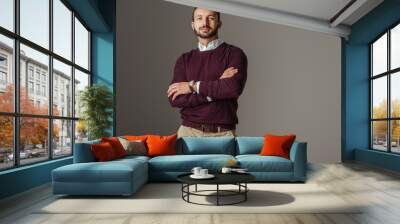 handsome man posing in burgundy autumn sweater with crossed arms, isolated on grey Wall mural