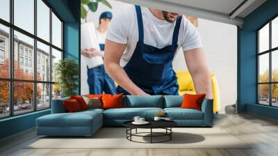 handsome mover in uniform wrapping cardboard box with scotch tape in apartment Wall mural