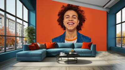 handsome stylish african american man in casual urban attire posing emotionally on orange background Wall mural