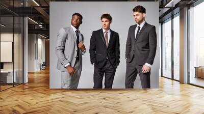 handsome stylish diverse male models in business elegant smart suits posing on gray backdrop Wall mural