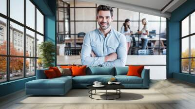 handsome young businessman with crossed arms smiling at camera in office Wall mural