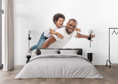 happy african american man piggybacking adorable son and imitating flying on white background Wall mural