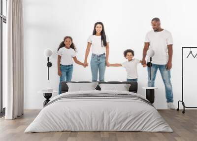 happy african american mother, father, daughter and son holding hands and smiling on white background Wall mural