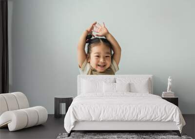 happy asian toddler girl with raised hands isolated on grey Wall mural