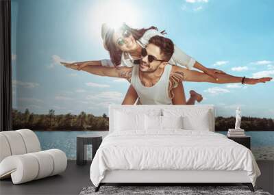 happy couple piggybacking while spending time on beach on summer day Wall mural