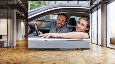 happy dad and teenage son looking at camera while sitting together in car. Wall mural