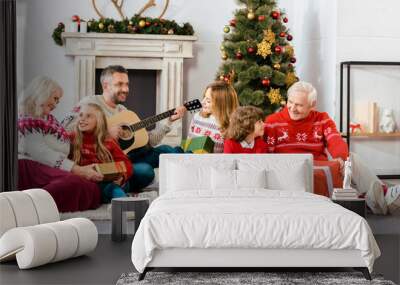 happy family sitting on floor together and listening guitar songs at home on christmas Wall mural