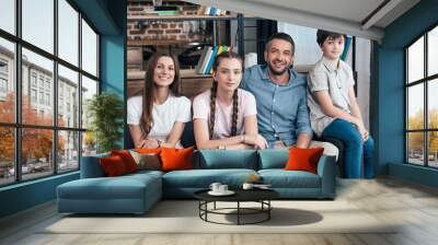 happy family with daughter and son sitting on sofa at home Wall mural