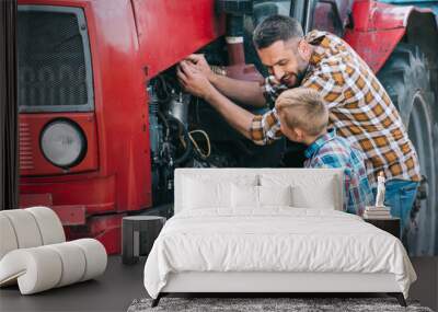 happy father and son repairing tractor engine together Wall mural