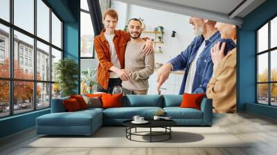 happy gay couple embracing near blurred parents and delicious supper in kitchen.  Wall mural