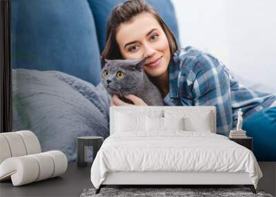 happy girl hugging cute grey cat and smiling at camera in bedroom Wall mural