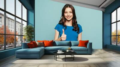 happy girl showing thumb up while smiling at camera isolated on blue Wall mural