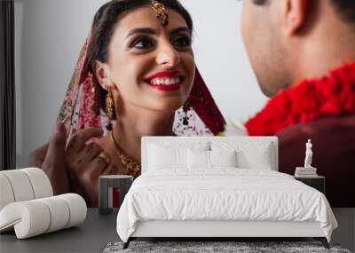 happy indian bride in headscarf looking at blurred bridegroom isolated on white Wall mural