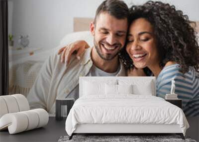 happy interracial couple smiling while looking at laptop Wall mural