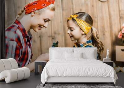 happy mother and daughter holding small plant with green leaves Wall mural