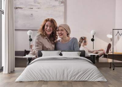 happy mother and sick adult daughter in kerchief laughing while sitting together Wall mural