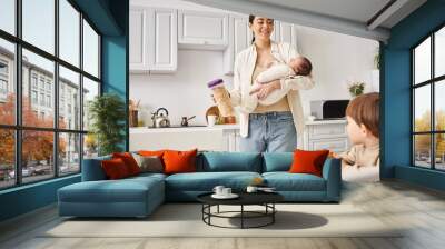 happy mother in casual attire holding cornflakes near her toddler son while holding her newborn Wall mural