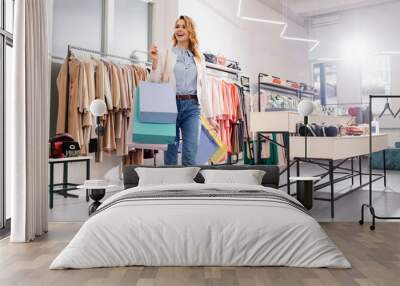 Happy shopaholic walking with shopping bags in showroom Wall mural