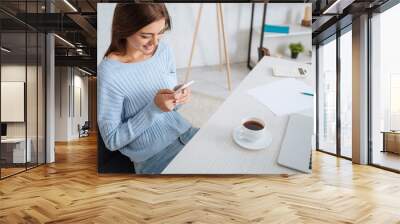 happy woman using smartphone near laptop and cup on table Wall mural