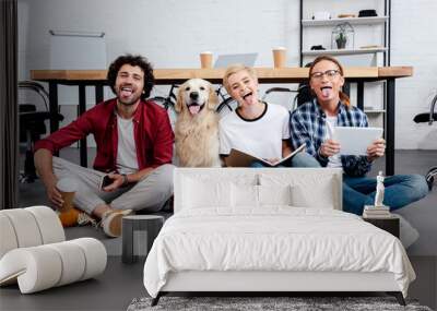 happy young business colleagues and dog sitting on floor with tongues out in office Wall mural