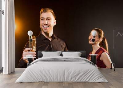 happy young couple with glasses of champagne standing on black Wall mural