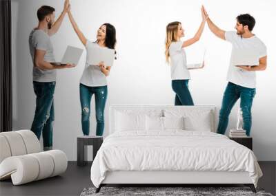 happy young couples holding laptops and giving high five isolated on white Wall mural