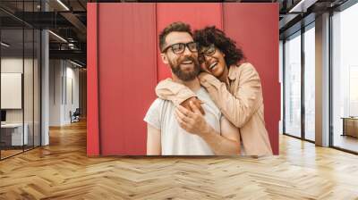 happy young multiethnic couple in eyeglasses hugging on street Wall mural