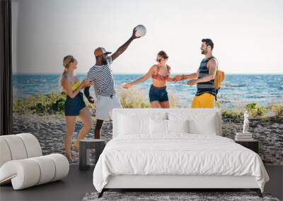 happy young multiethnic friends playing with ball on sandy beach Wall mural