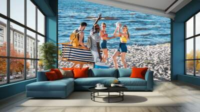 happy young multiethnic friends with beach items smiling each other on sandy sea coast Wall mural