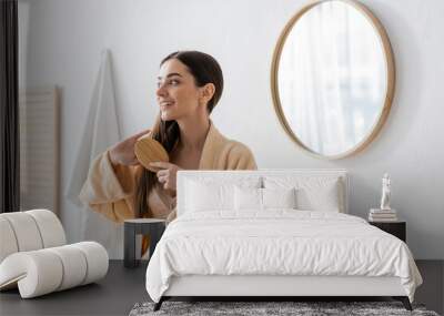 happy young woman in bathrobe brushing hair in white modern bathroom. Wall mural