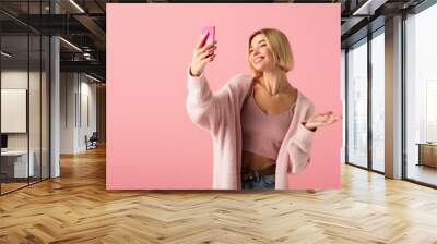 happy young woman in soft cardigan taking selfie isolated on pink. Wall mural