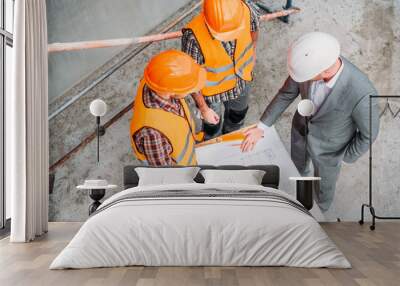 high angle view of builders and architect discussing blueprint at construction site Wall mural