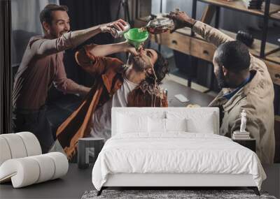 high angle view of man drinking from funnel while friends pouring alcohol beverages Wall mural