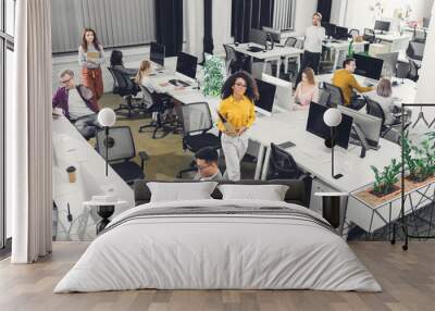 high angle view of multiracial young business people working with computers and documents in open space office Wall mural