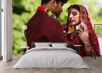 indian bridegroom adjusting headscarf on bride in sari Wall mural