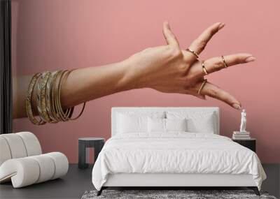 indian woman showcasing gold bangles on her hand in a stylish pose. Wall mural