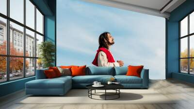 jesus praying with closed eyes in desert against blue sky Wall mural