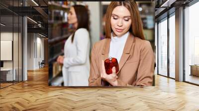 joyful attractive women in business casual attires choosing new perfumes in cosmetics store Wall mural