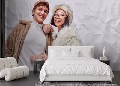 joyful interracial couple in fashionable warm outwear on white textured backdrop, winter fashion Wall mural