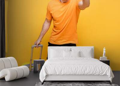 late yelling man in headphones running with travel bag on yellow Wall mural