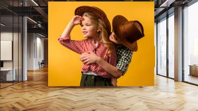 little cowboy embracing stylish cowgirl, isolated on yellow Wall mural