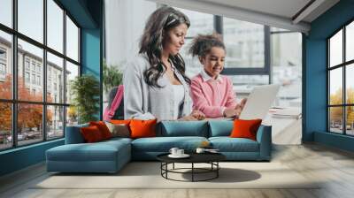 little daughter helping mother working on laptop at business office, work and life balance concept Wall mural