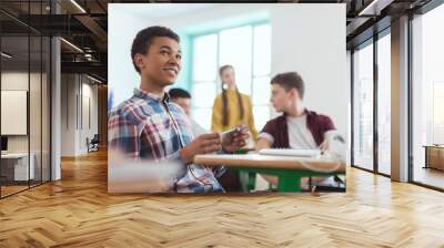 Low angle view of african american high school student holding pencil in hand and classmates sitting behind Wall mural