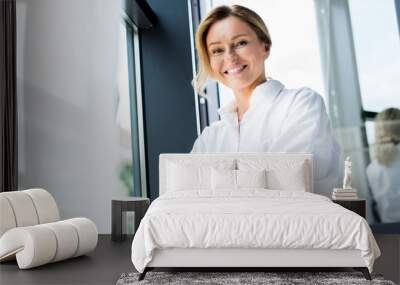 low angle view of attractive businesswoman standing with crossed arms in office Wall mural