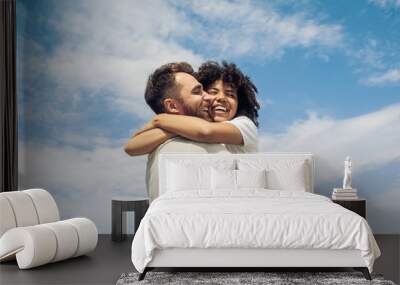 low angle view of happy young multiracial couple hugging against blue sky Wall mural